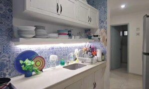 A kitchen with white cabinets, a sink, and a countertop with dishes and utensils. - Beachfront Apartment | Ground Floor and Pool (Progreso)