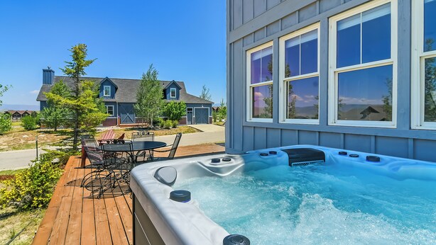 Un bain à remous sur une terrasse en bois, avec une maison en arrière-plan.