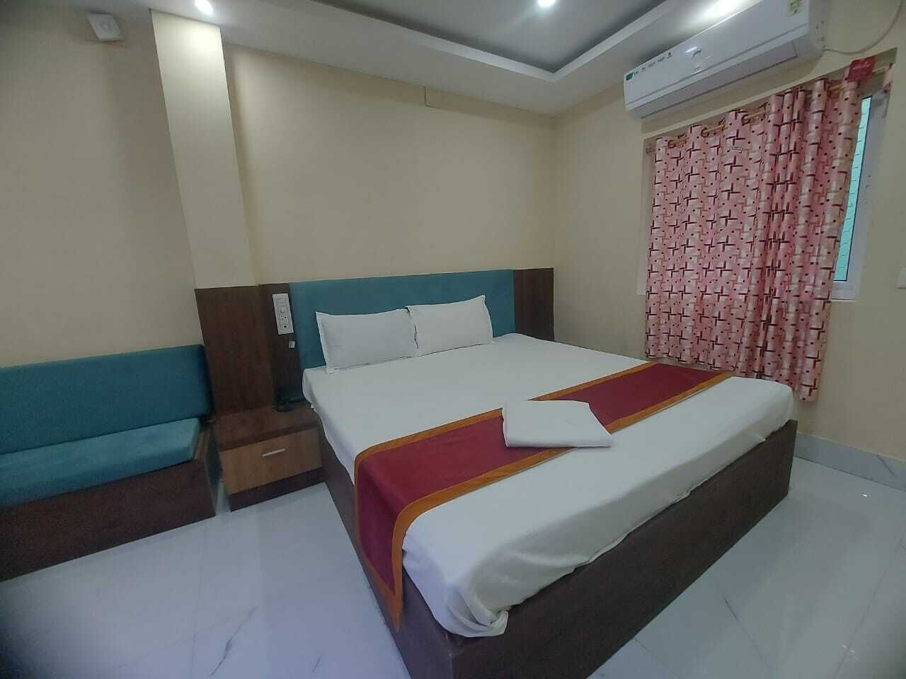Une chambre d’hôtel comprenant un lit, une table de chevet, un banc et un appareil de climatisation.