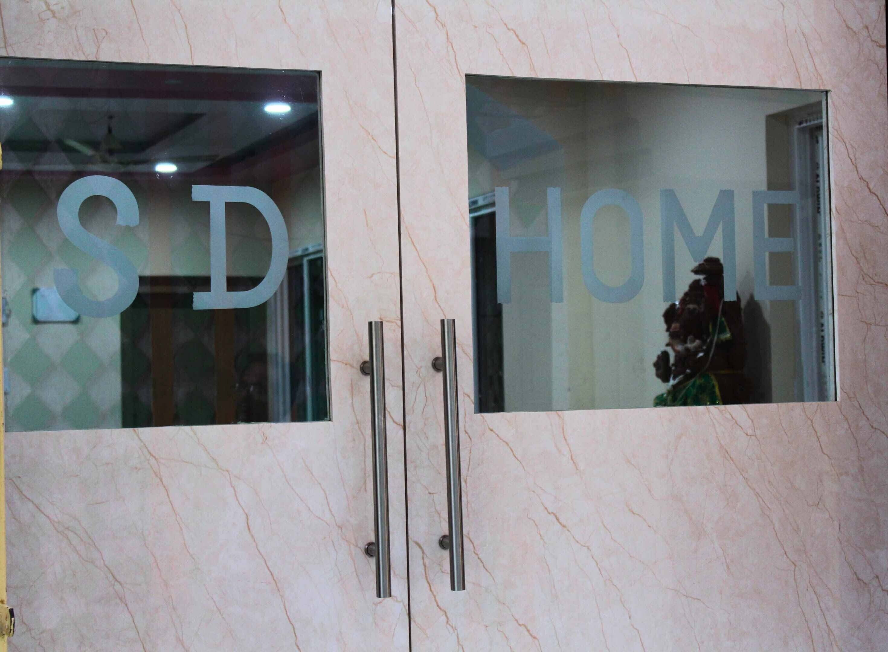 A hotel entrance with 'SD' and 'HOME' signs on glass doors.