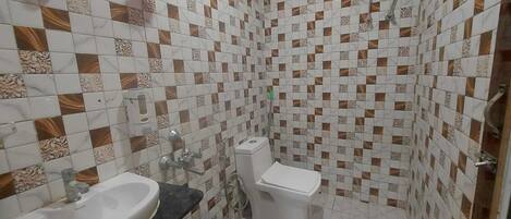 A bathroom with a sink, toilet, shower, and a blue bucket.