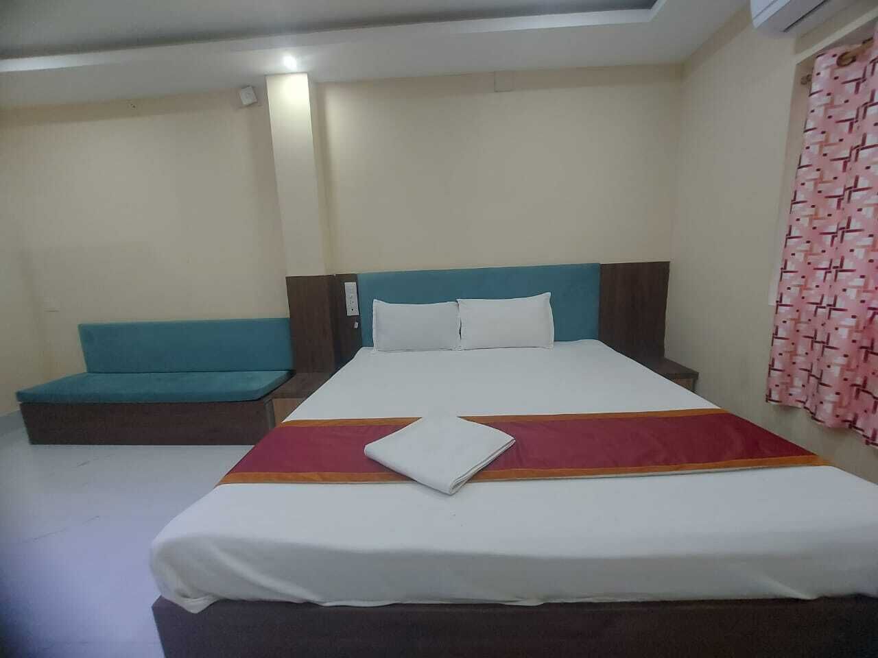 Ein Hotelzimmer mit Bett, Sitzbank und einem fenster mit Vorhängen.