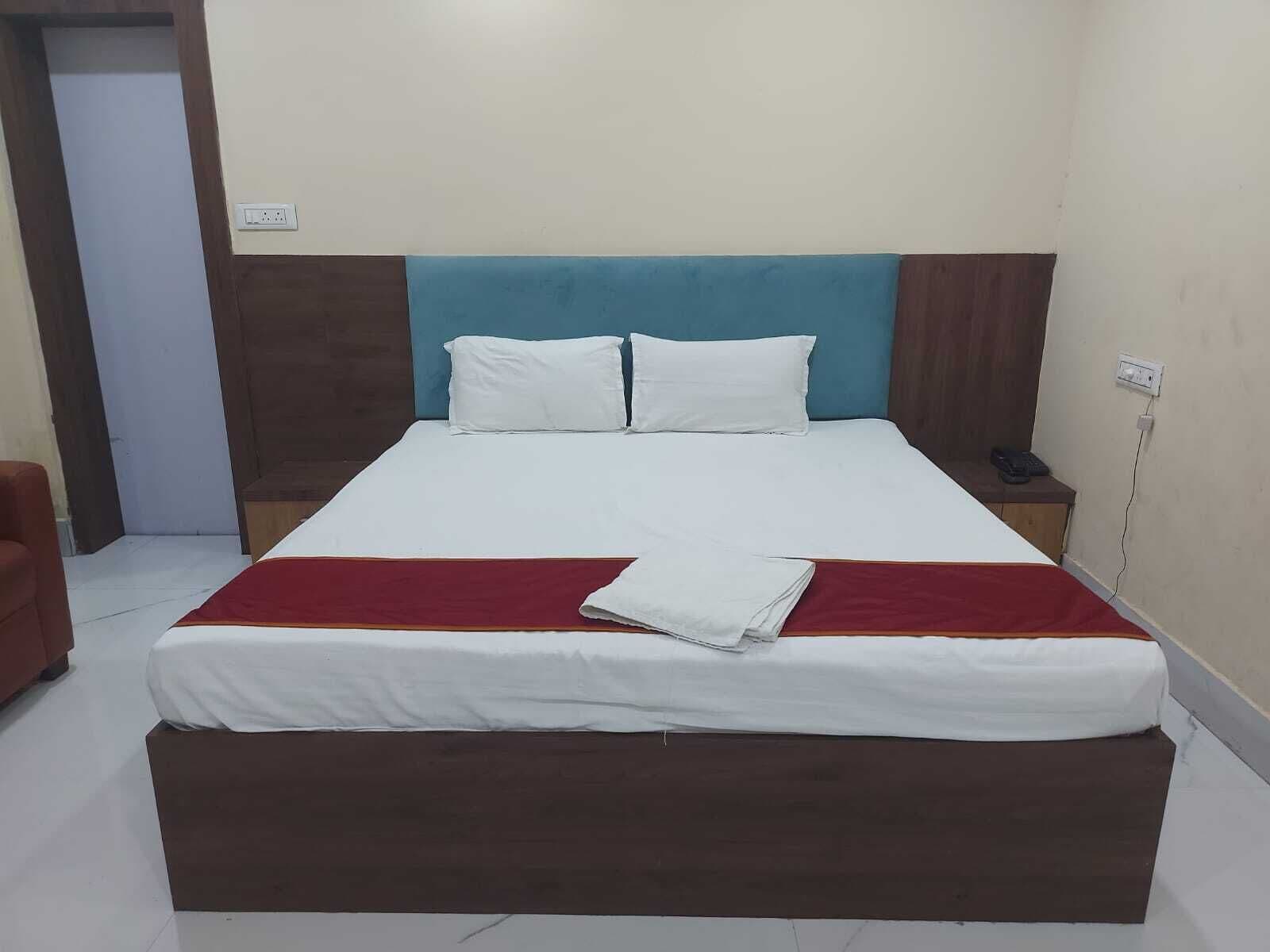 A hotel room with a bed, a nightstand, a chair, and a door.