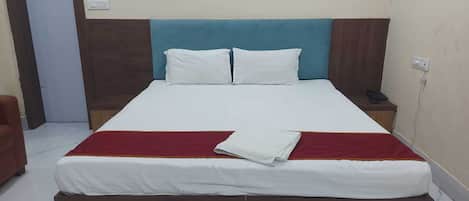 A hotel room with a bed, a nightstand, a chair, and a door.