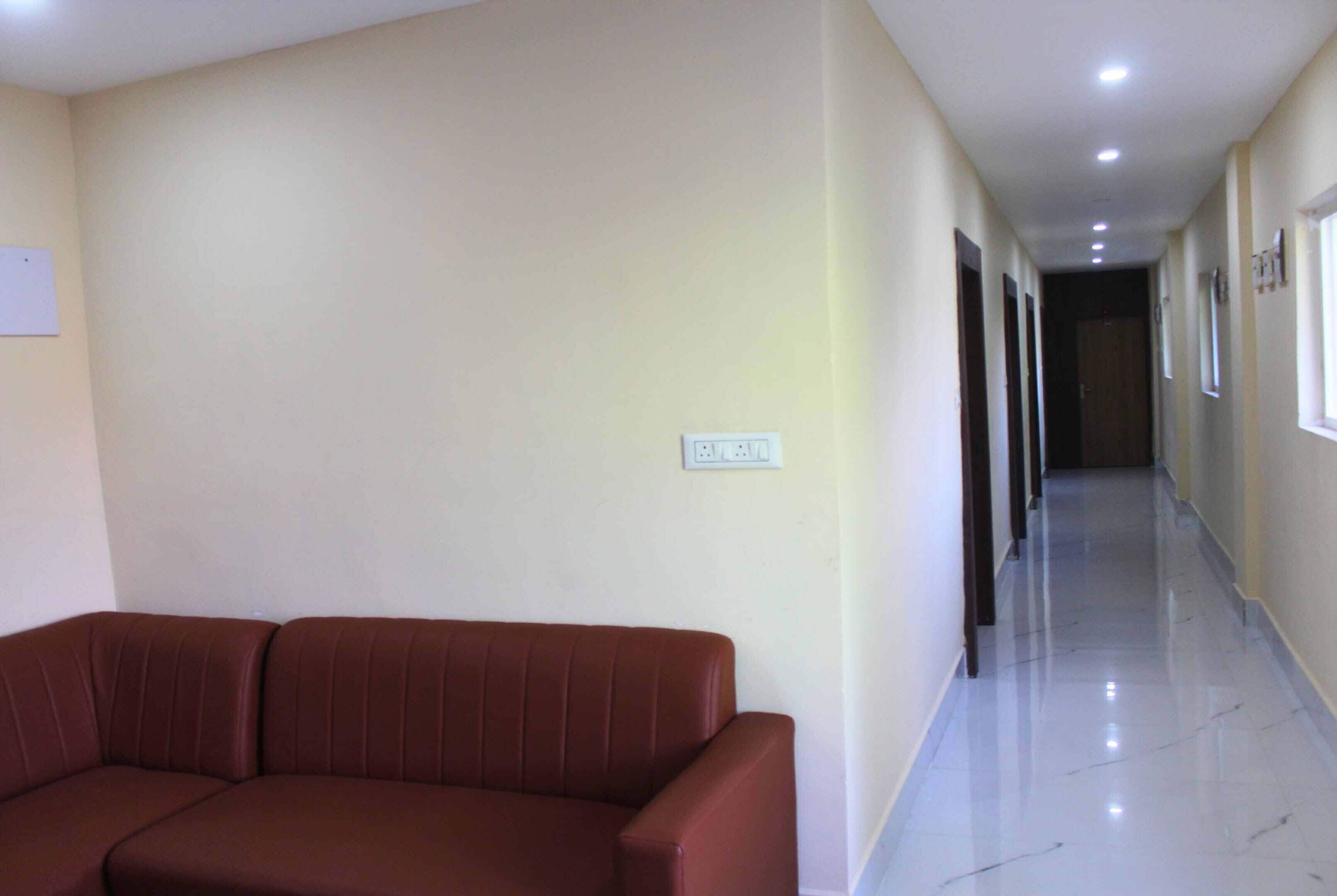 A hallway with a brown sofa, a light-colored wall, and a ceiling with recessed lighting.