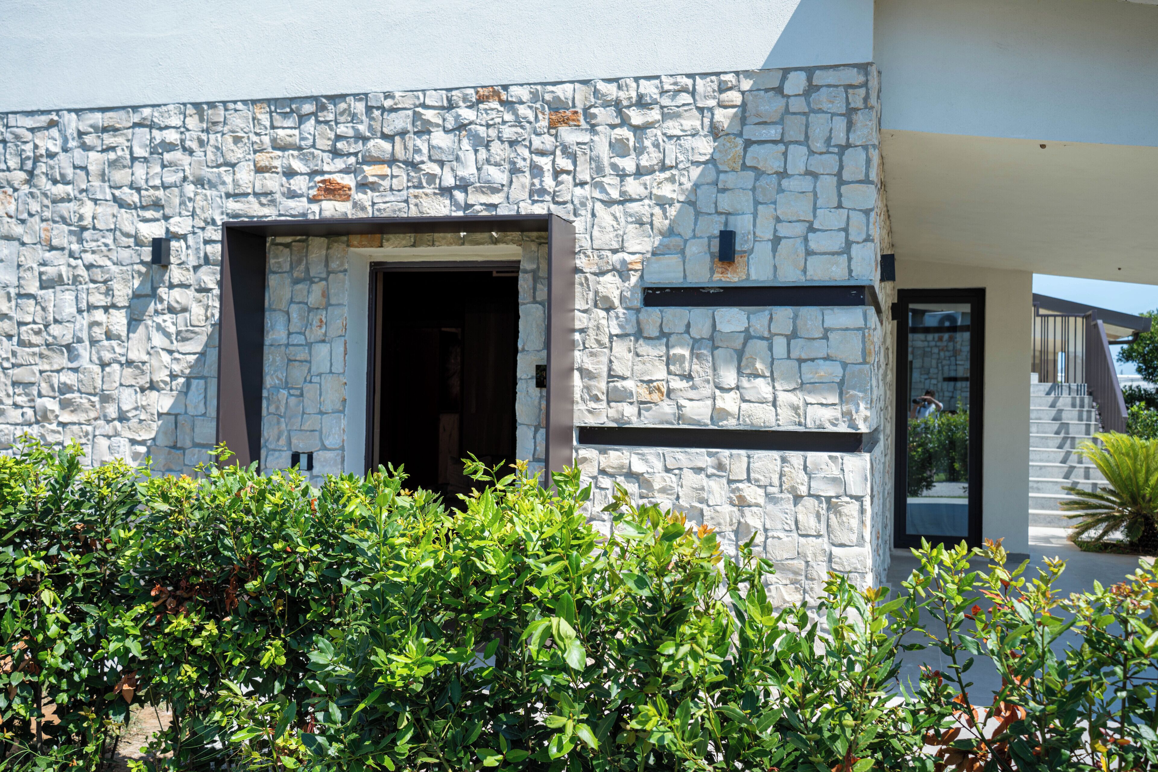 A modern building with a stone facade, a doorway, and a small window.