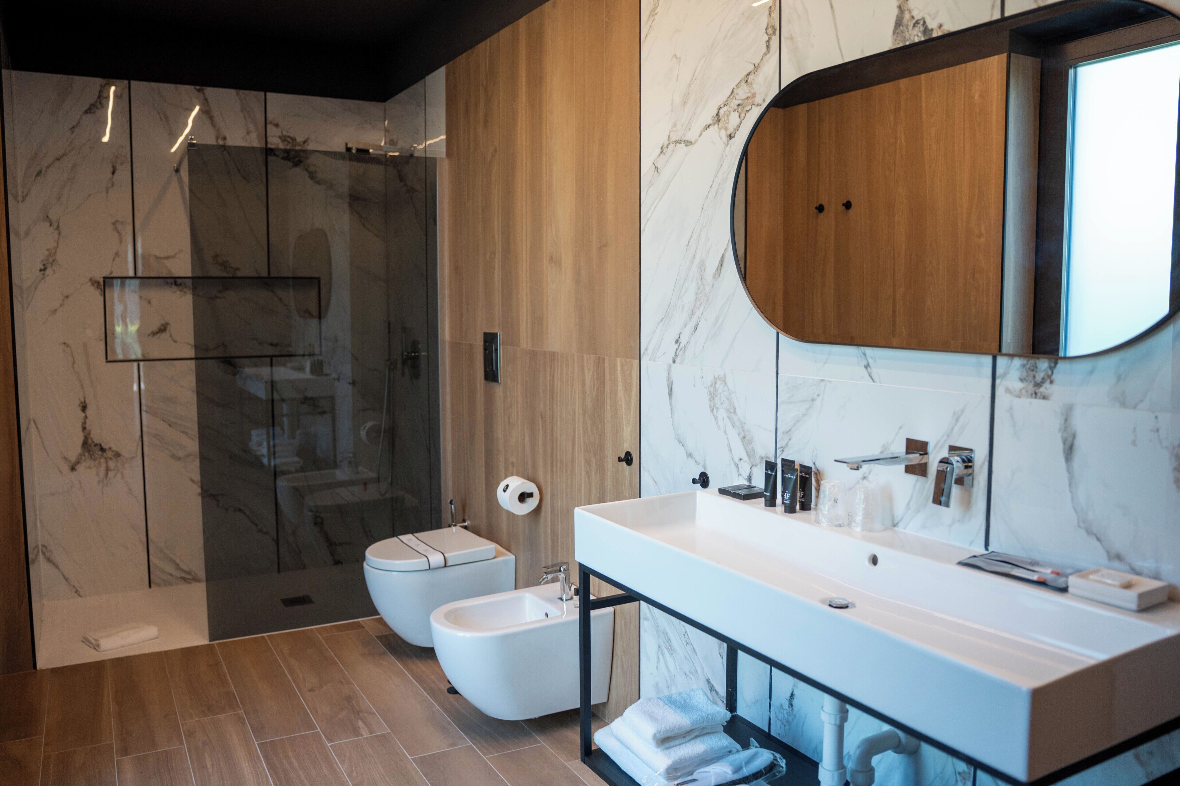 Ein modernes Badezimmer mit Marmorwaschtisch, einer Duschkabine aus Glas und einem Bidet.