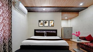Una habitación de hotel moderna con una cama, un sofá, una mesita y un jarrón decorativo.