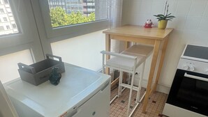 Una cocina compacta con refrigerador, una mesita, un lavamanos y estufa.