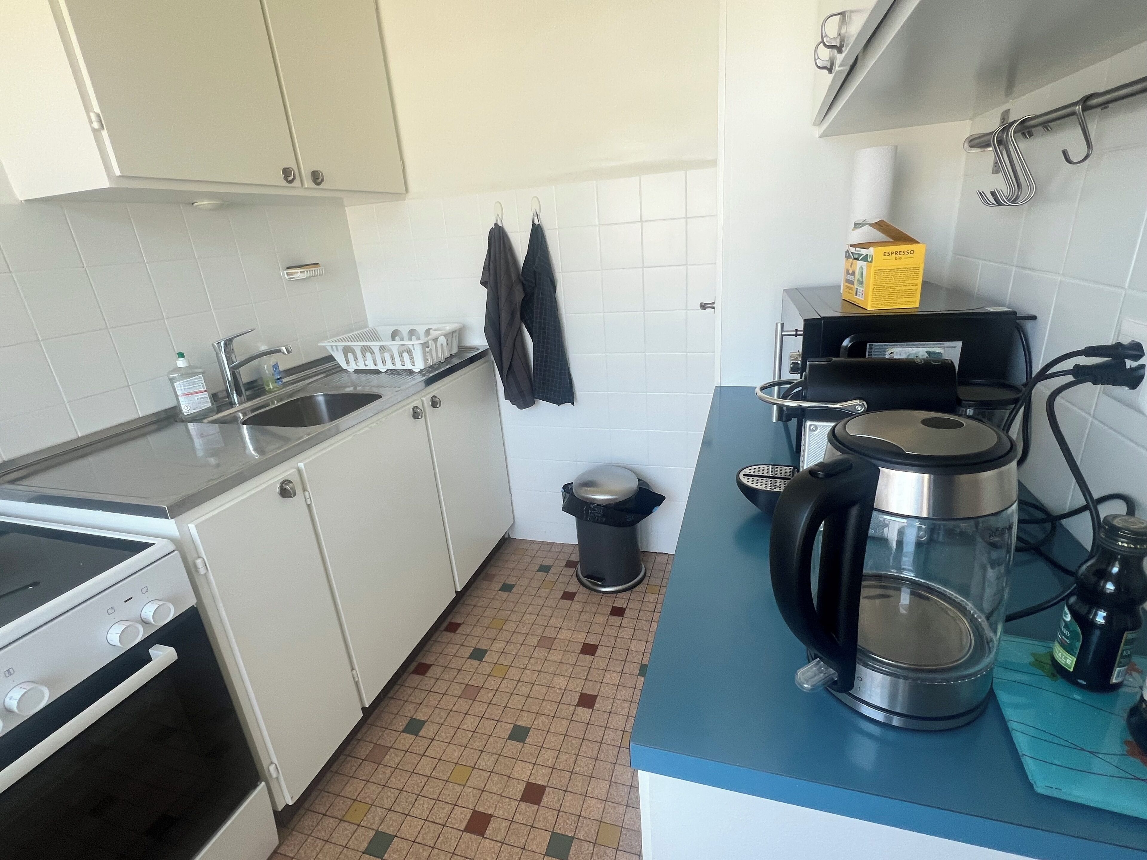 A compact kitchen with a stove, sink, and coffee maker.