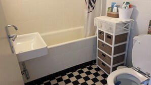Un baño con una bañera blanca, un lavabo, un inodoro y un suelo a cuadros.