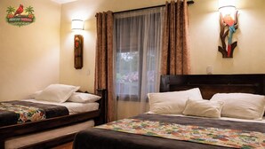 Una camera d'albergo con due letti, un comodino, una lampada a parete e una finestra con tende.