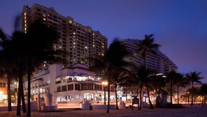 Un hotel de gran altura con varios pisos, un atrio central y ubicación frente a la playa.