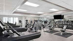 Un gimnasio con cintas de correr, máquinas de pesas y una pantalla de televisión.