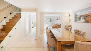 A modern interior with a staircase, a dining area with a glass table, and a painting on the wall. - Historic, elegant and luxurious home in St John's Wood, central London (London)