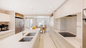 A modern kitchen with a central island, double sinks, and stainless steel appliances. - Historic, elegant and luxurious home in St John's Wood, central London (London)