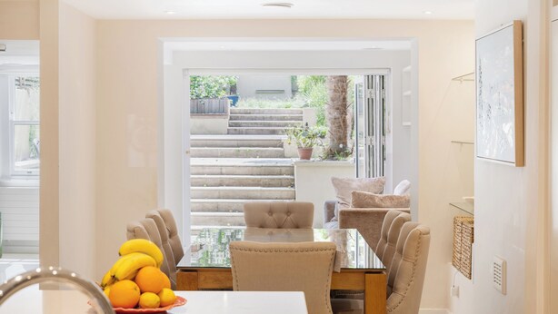 A dining area with a table, chairs, and a view of outdoor stairs and greenery. - Historic, elegant and luxurious home in St John's Wood, central London (London)