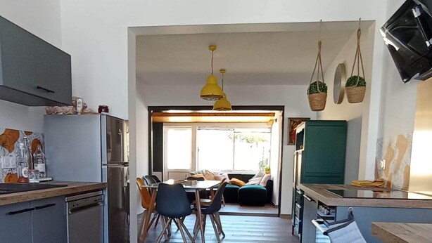 A modern kitchen with a dining area, wooden flooring, and a view to the outside. - Gaby's Little House (Saint-Hilaire-de-Riez)