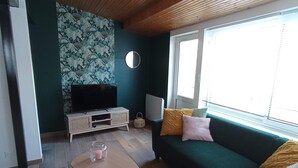 A living room with a green sofa, a round mirror, a television, and a wooden ceiling. - Gaby's Little House (Saint-Hilaire-de-Riez)