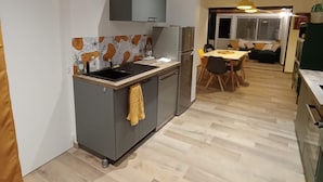 A modern kitchen with grey cabinets, a patterned backsplash, and a yellow towel hanging on the door. - Gaby's Little House (Saint-Hilaire-de-Riez)