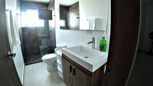 Un baño con inodoro, lavamanos y zona de ducha.