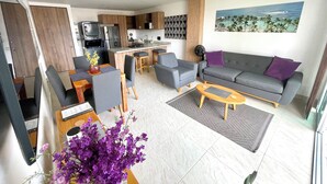 Una sala de estar moderna con un sofá gris, una mesa de centro y una zona de comedor con una mesa y sillas.
