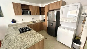Una cocina moderna con encimeras de granito, electrodomésticos de acero inoxidable y armarios de madera.