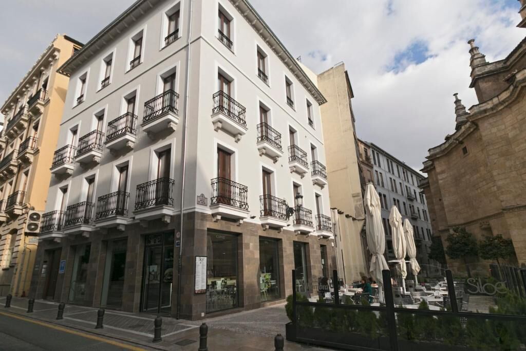 Un edificio de varios pisos con balcones, locales comerciales y terraza.