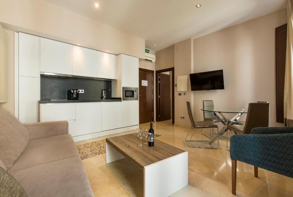 Un salon moderne comprenant un canapé, une table basse, un téléviseur et un coin repas avec des chaises et une table en verre.