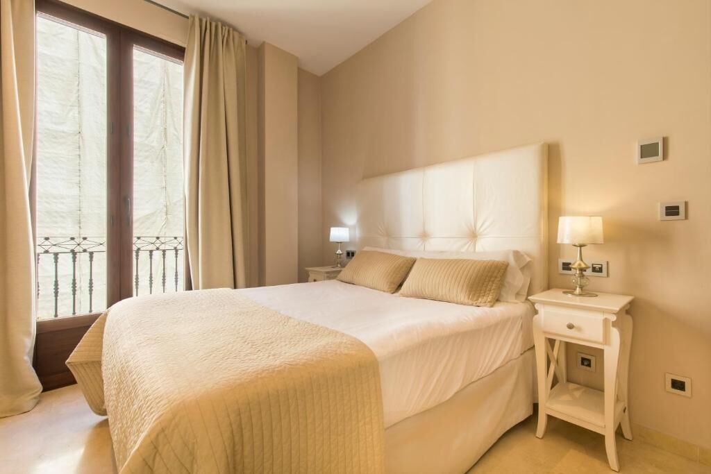 Een hotelkamer met een bed, nachtkastjes, een raam met gordijnen en een balkon.