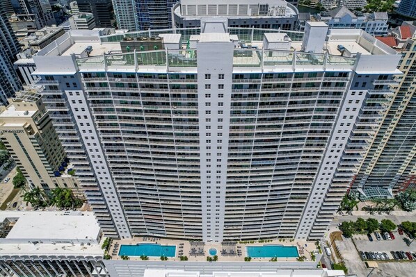 A high-rise hotel with multiple balconies, a rooftop pool, and a modern architectural design. - Brickell 2BR Escape | Stunning Water & City Views (Miami)