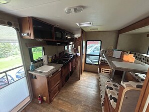 Eine kompakte Küchenzeile für Wohnmobile mit Spüle, Herd, Mikrowelle und einer kleinen Essecke.