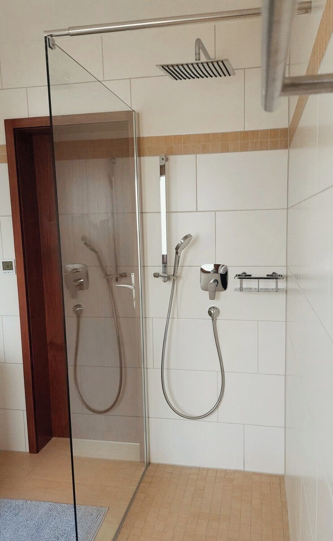 Eine Duschkabine mit Handbrause und am Wand montiertem Wasserhahn.