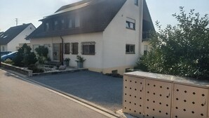 Ein Wohngebäude mit geneigtem Dach, einer Veranda und einem Schotterweg.