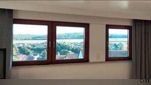 Ein Zimmer mit drei Fenstern und Blick auf eine ländliche Landschaft.