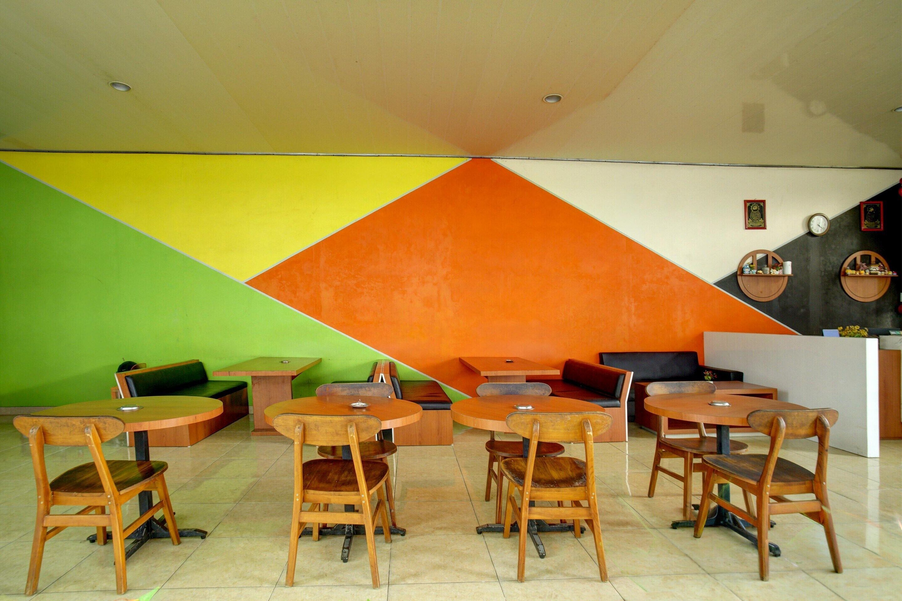 A dining area with wooden tables and chairs, a green sofa, and a reception desk.