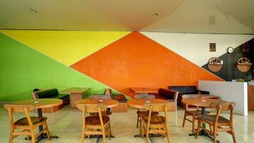 A dining area with wooden tables and chairs, a green sofa, and a reception desk.