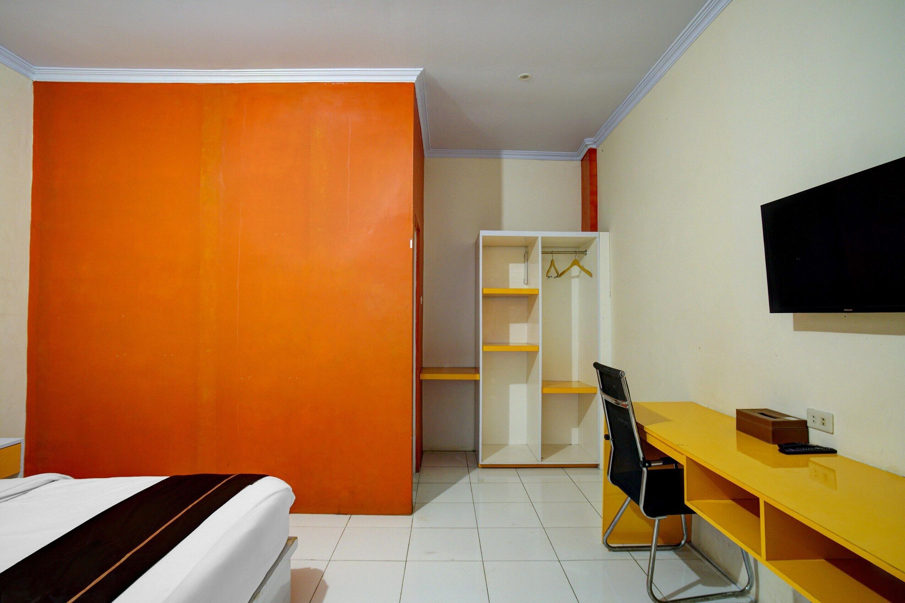 A room with a bed, a desk, a chair, a wardrobe, and a television.