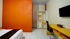 Ein Zimmer mit einem Bett, einem Schreibtisch, einem Stuhl, einem Kleiderschrank und einem Fernseher.