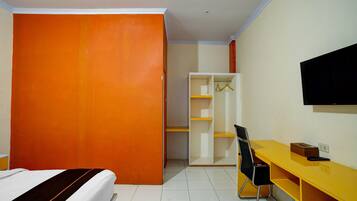 A room with a bed, a desk, a chair, a wardrobe, and a television.