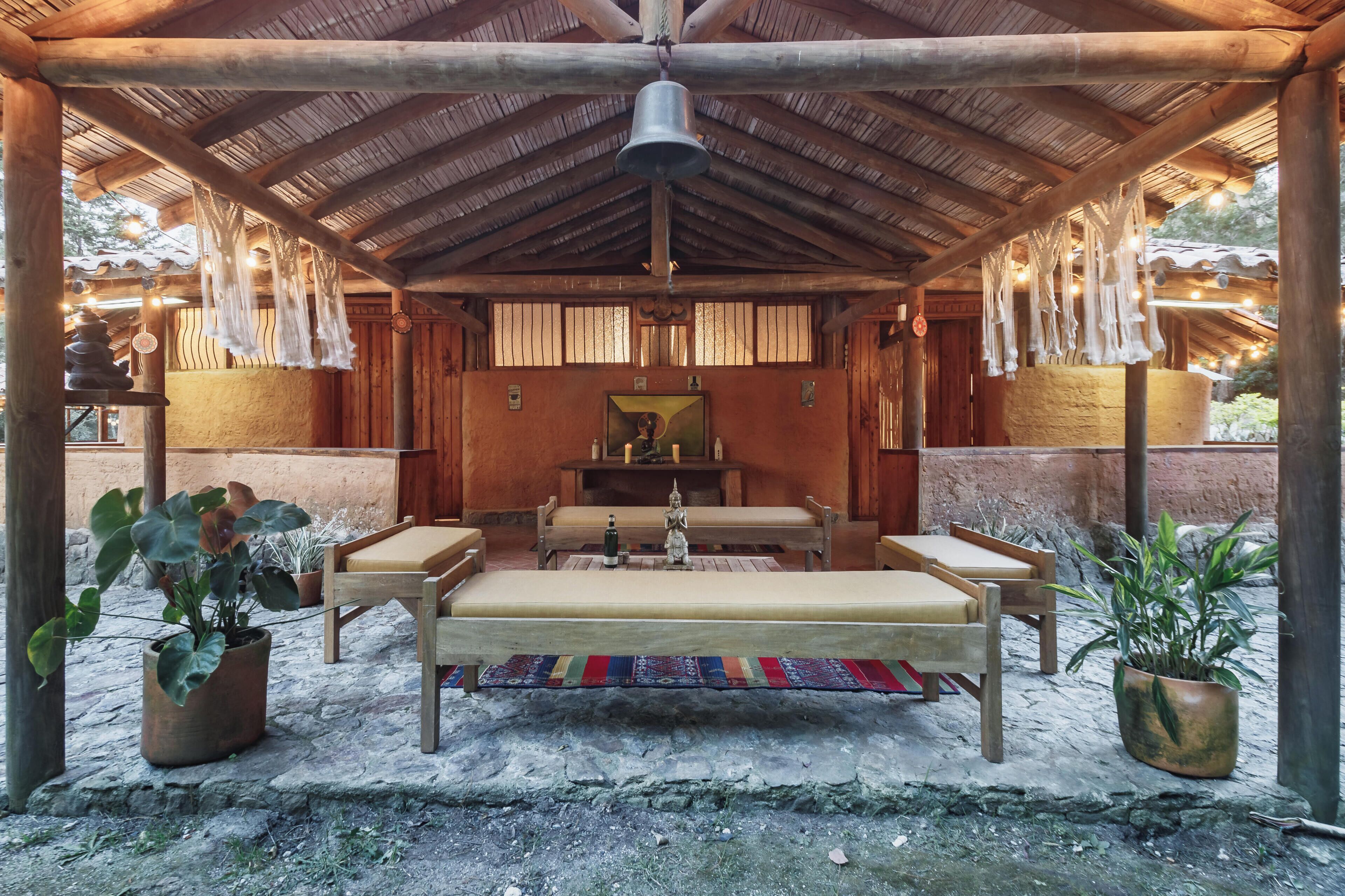 Un área de estar al aire libre cubierta con un banco, mesas y decoraciones colgantes.