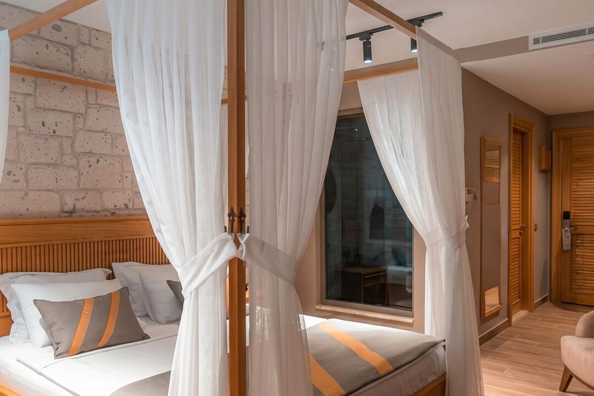 A bedroom with a four-poster bed, a brick wall, and a wooden floor.