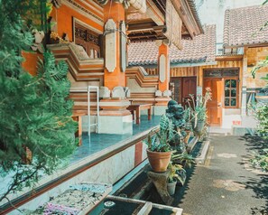 A traditional building with a tiled roof, a wooden door, and a small garden area with potted plants.