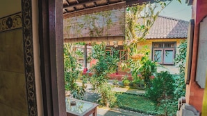 Un patio tradicional con suelo de baldosas, plantas en macetas y una mesa de madera.