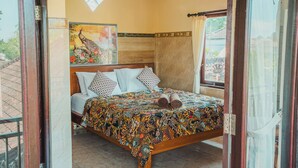 Un dormitorio con una cama, un ventilador de techo, una ventana con cortinas y una pared decorativa.