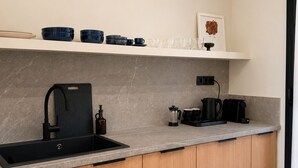 Una cucina moderna con lavello nero, mobili in legno, piano di lavoro in marmo e macchina da caffè.