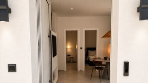 Un corridoio che porta a una camera da letto con un letto, una sedia e una lampada.