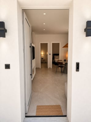 Ein Flur, der zu einem Schlafzimmer mit einem Bett, einem Sessel und einer Lampe führt.