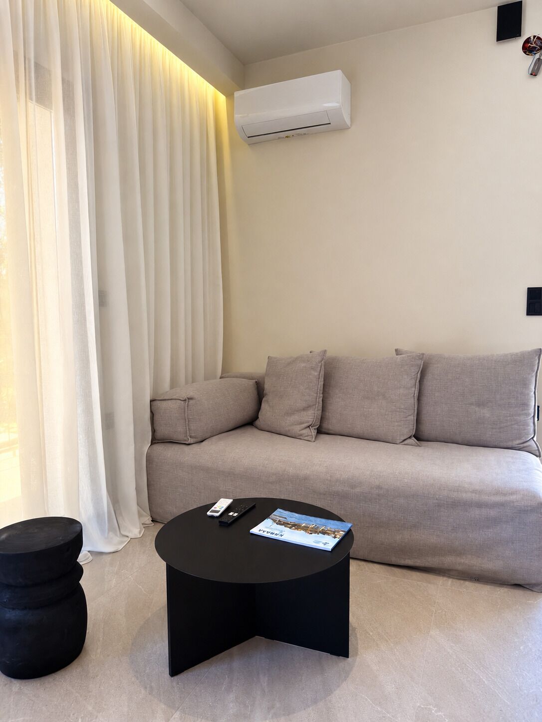 A modern living room with a sofa, a black coffee table, and a remote control.