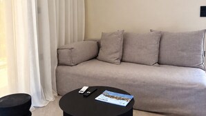 Un soggiorno moderno con un divano, un tavolino da caffè nero e un telecomando.